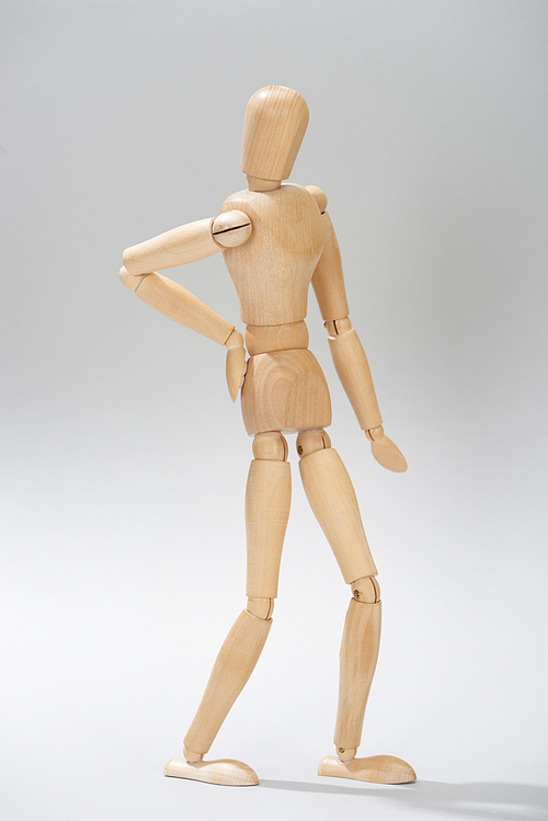 Wooden doll with hand on hip on grey background