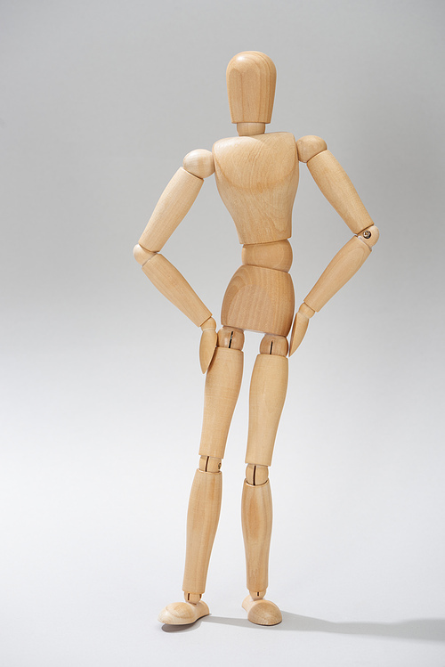 Wooden dummy with hands on hips on grey background