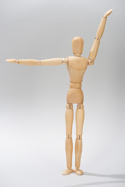 Wooden puppet with raised hands on grey background
