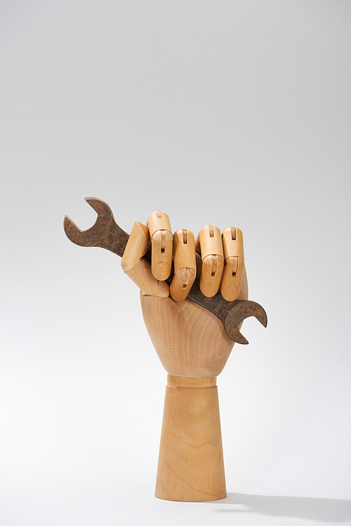 Wooden hand of doll with adjustable wrench on grey background
