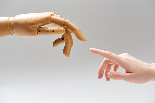 Cropped view of woman and hand of wooden doll pulling fingers to each other isolated on grey