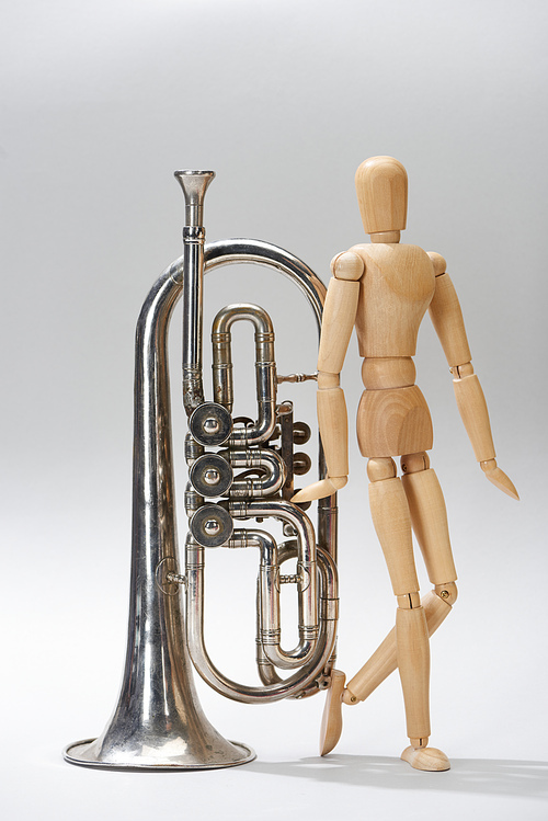 Alto horn with wooden puppet on grey background