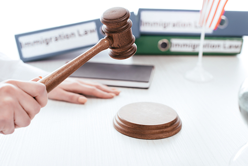 selective focus of gavel in hand of female judge with folders on background