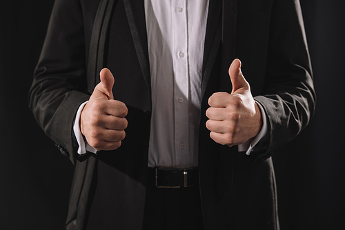 man in formal wear showing thumbs up isolated on black