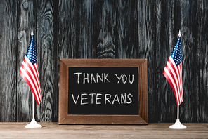 black board with thank you veterans lettering near flags of america