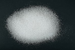 top view of white granulated sugar crystals on black background