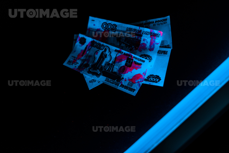 유토이미지 | blue ultraviolet lightning on russian money on black