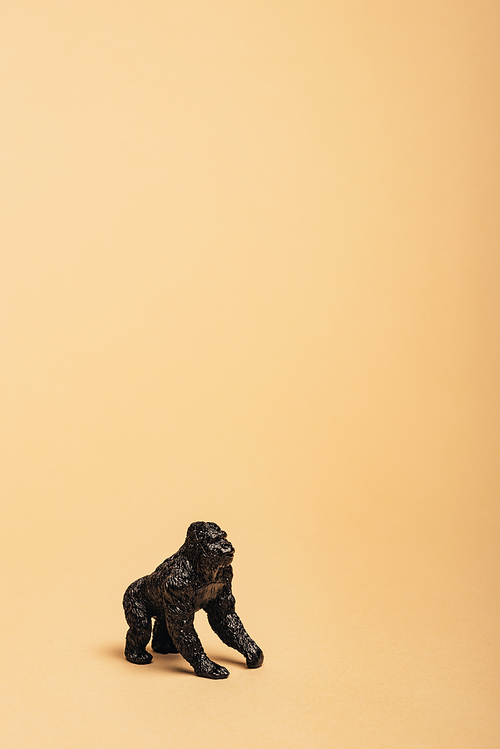 Black toy gorilla on yellow background, animal welfare concept