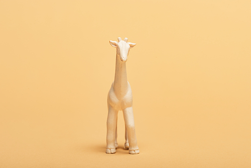 White toy giraffe on yellow background, animal welfare concept