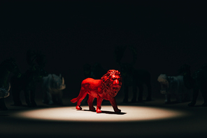 Red toy lion under spotlight with animals at background, voting concept