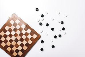 Top view of checkers by wooden checkerboard on white background