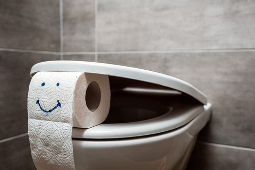 close up view of ceramic clean toilet bowl and toilet paper with smiley face in modern restroom