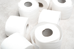 close up view of rolls of toilet paper on grey textured surface