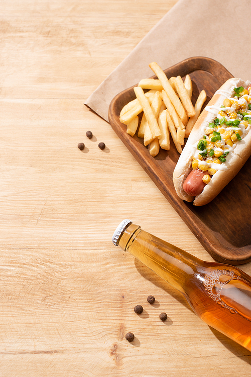 delicious hot dog with corn, green onion and mayonnaise near beer and french fries on wooden table