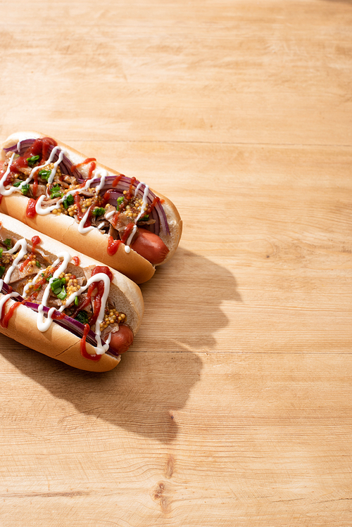 delicious hot dogs with red onion, bacon and Dijon mustard on wooden table