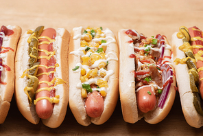fresh various tasty hot dogs with vegetables and sauces on wooden table