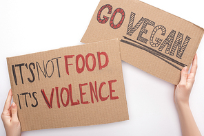 partial view of woman holding cardboard signs with go vegan and its not food its violence inscriptions on white background