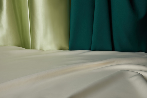 close up view of emerald, light green and white soft and wavy silk fabric