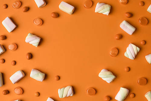 top view of tasty marshmallows and sweet candies on orange