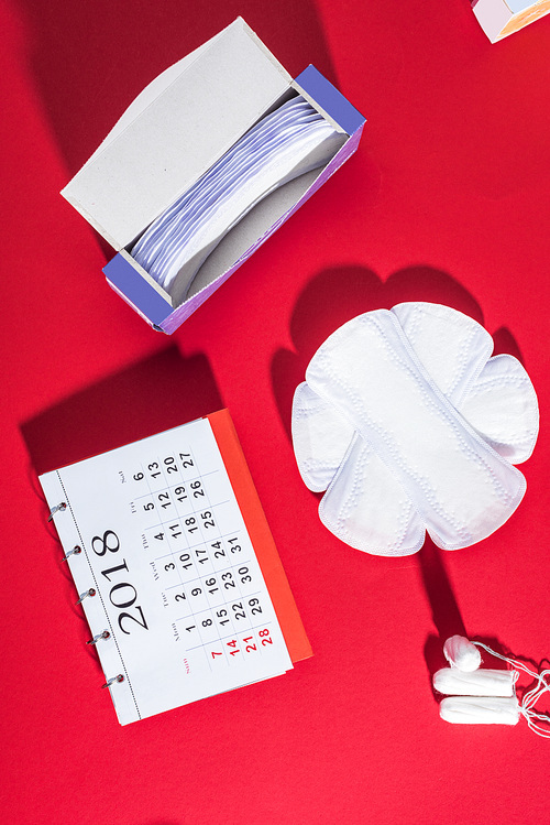 top view of menstrual tampons, daily liners and calendar on red