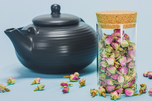 close-up view of 홍차pot and dry rose buds in glass jar on blue