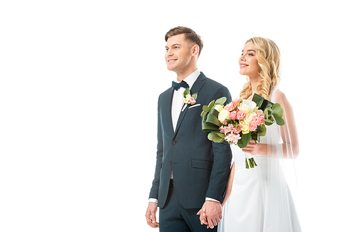 happy bride with beautiful wedding bouquet holding hands with smiling groom isolated on white