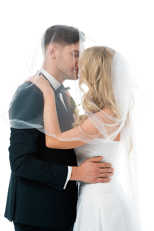 bride kissing groom while covering him with bridal veil isolated on white