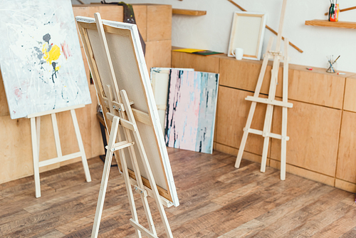 painting studio with wooden floor, cabinets, easels and paintings