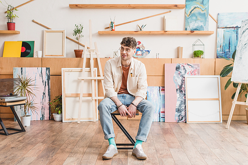 handsome smiling artist sitting on chair in spacious light gallery