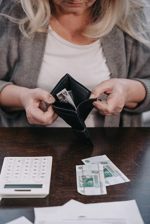 cropped view of senior woman holding wallet with money