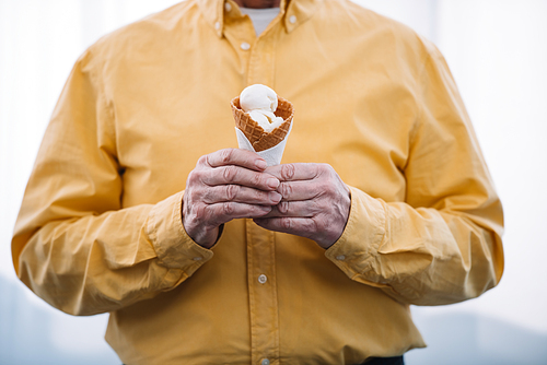 cropped view of senior man holding ice cream cone