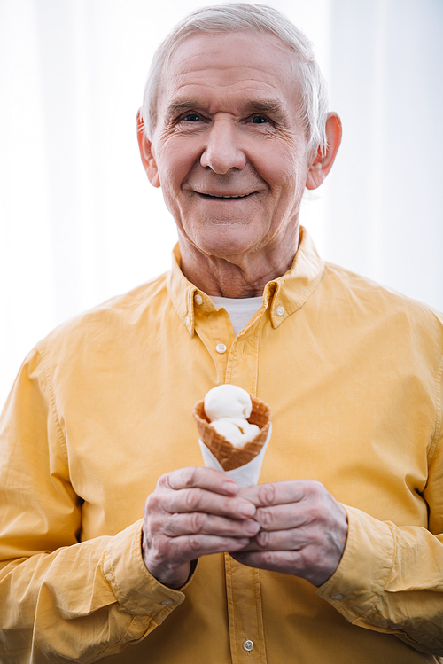 senior man  and holding ice cream cone at home
