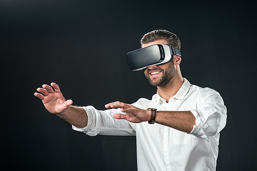 smiling man using virtual reality headset, isolated on black