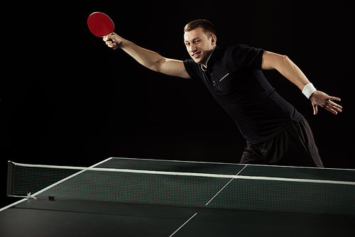 young tennis player playing table tennis isolated on black