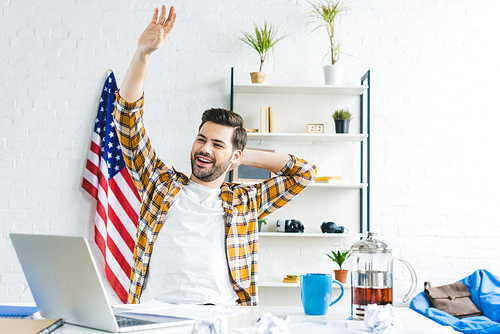 Smiling man stretching by working table at home office