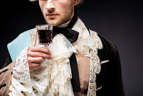 cropped view of victorian man holding wine glass on black