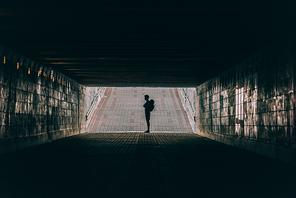 side view of young adult man with backpack in tunnel