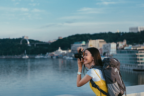 side view of asian woman with backpack taking photo