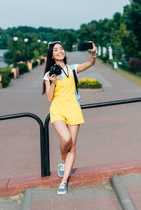 asian and attractive woman holding digital camera and taking selfie