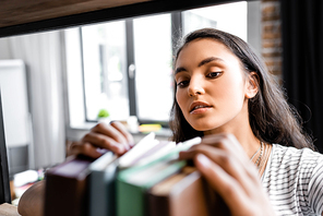 selective focus of bi-racial student holding books in apartment