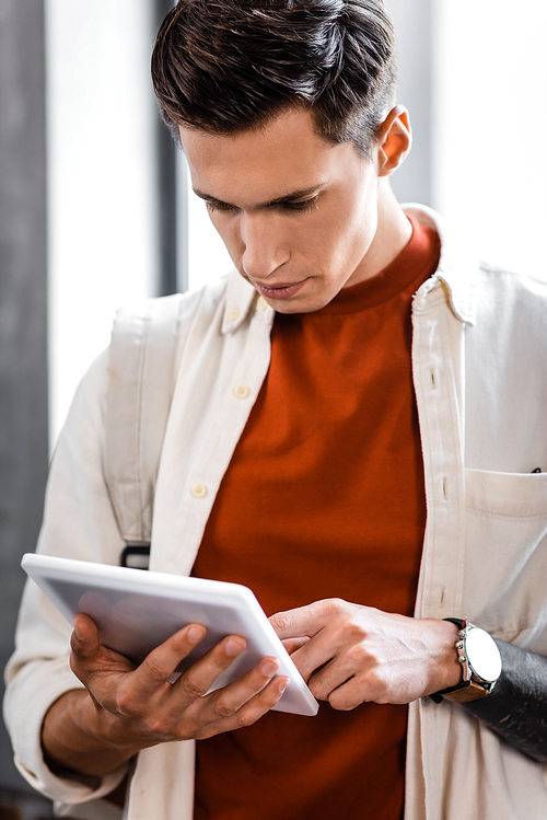 handsome student in shirt using digital tablet in apartment