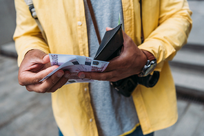 cropped view of mixed race man holding wallet while counting money