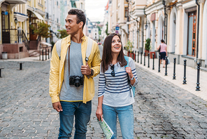 happy woman walking with cheerful bi-racial man