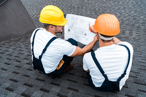 overhead view of builders in helmets looking at blueprint