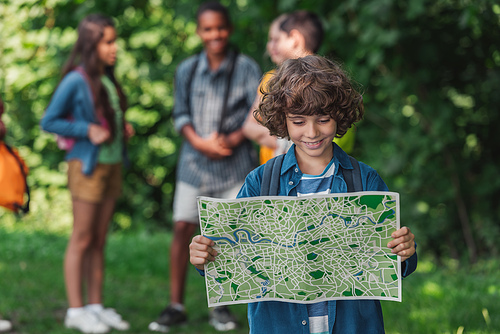 selective focus of happy and curly boy looking at map