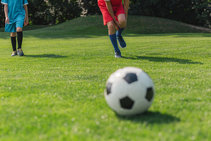 selective focus of boy touching leg near friend near football