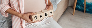 panoramic shot of pregnant woman holding wooden blocks with word baby