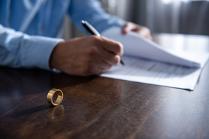 partial view of man sitting at table and signing divorce documents