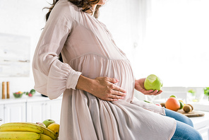 cropped view of pregnant woman holding apple