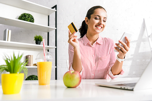 selective focus of attractive girl using smartphone and holding credit card